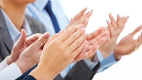 3 business professionals in suits clapping hands
