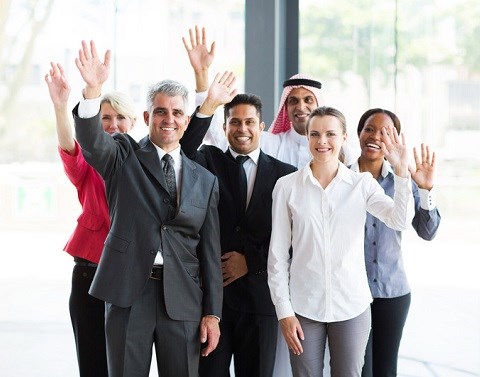 Multi-national group of male and female business professionals waving.