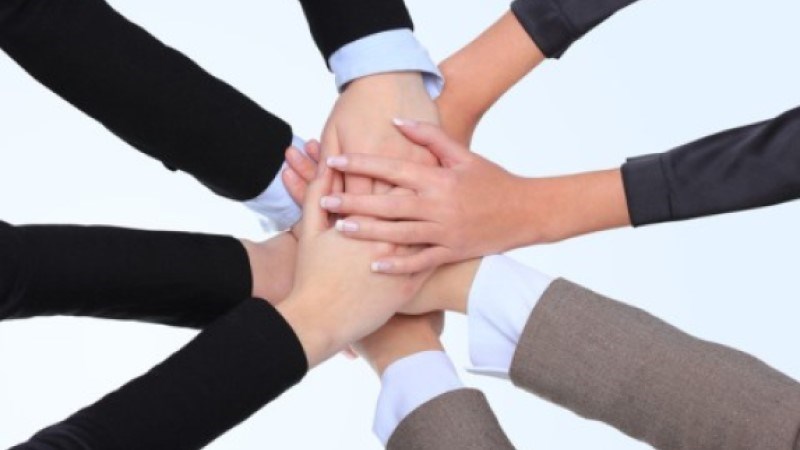 Four businesswomen in a circle stack hands palms down.