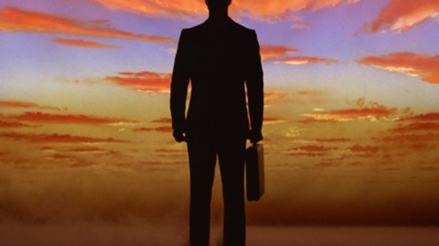 Silhouette of businessman standing against cloudy sunset