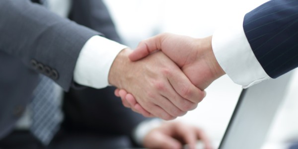 Two businessmen shaking handswith a open laptop between them