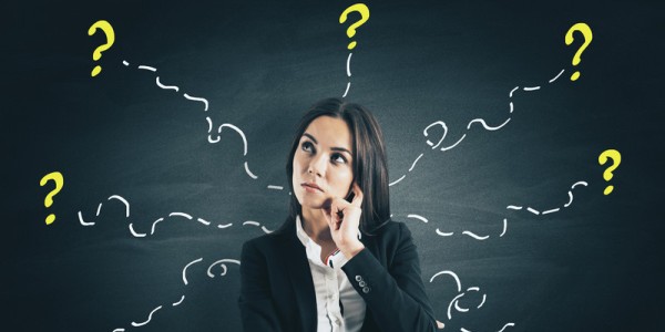 Behind a thinking businesswoman is a blackboard with wavy, curly dashed lines extending outward towards question marks