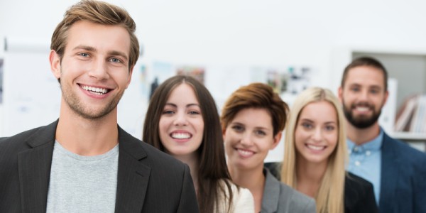 Five young male and female professionals are a line and smiling.