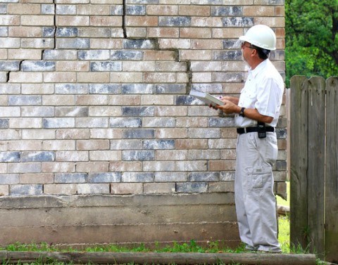 Man in hard hat evaluating foundation damage