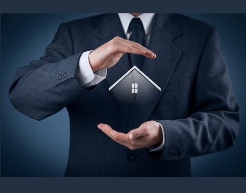 Businessman with his hands protecting a hologram of the top of a house